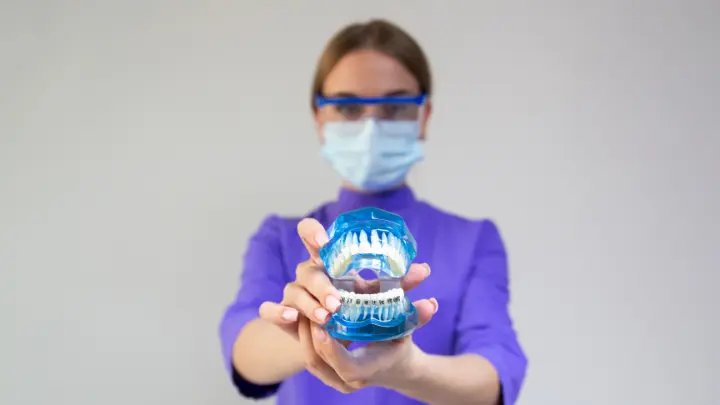 A dentist holding up blue fake teeth