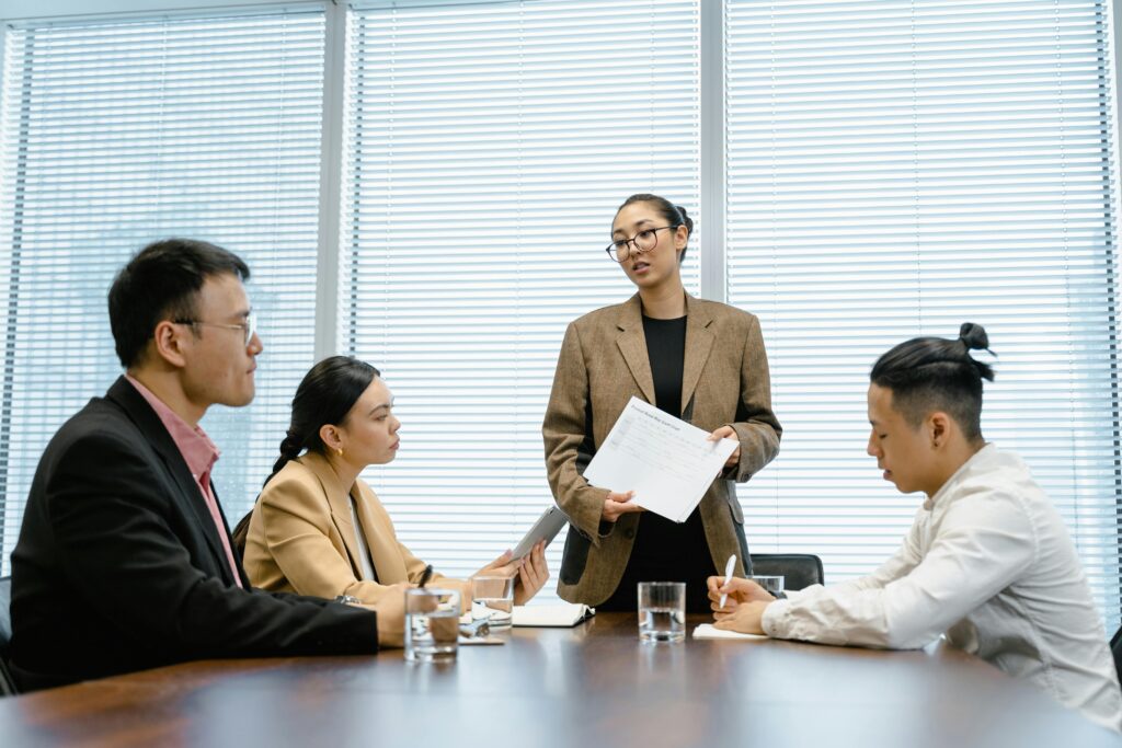 Woman Standing Up in Front of Colleagues During Meeting